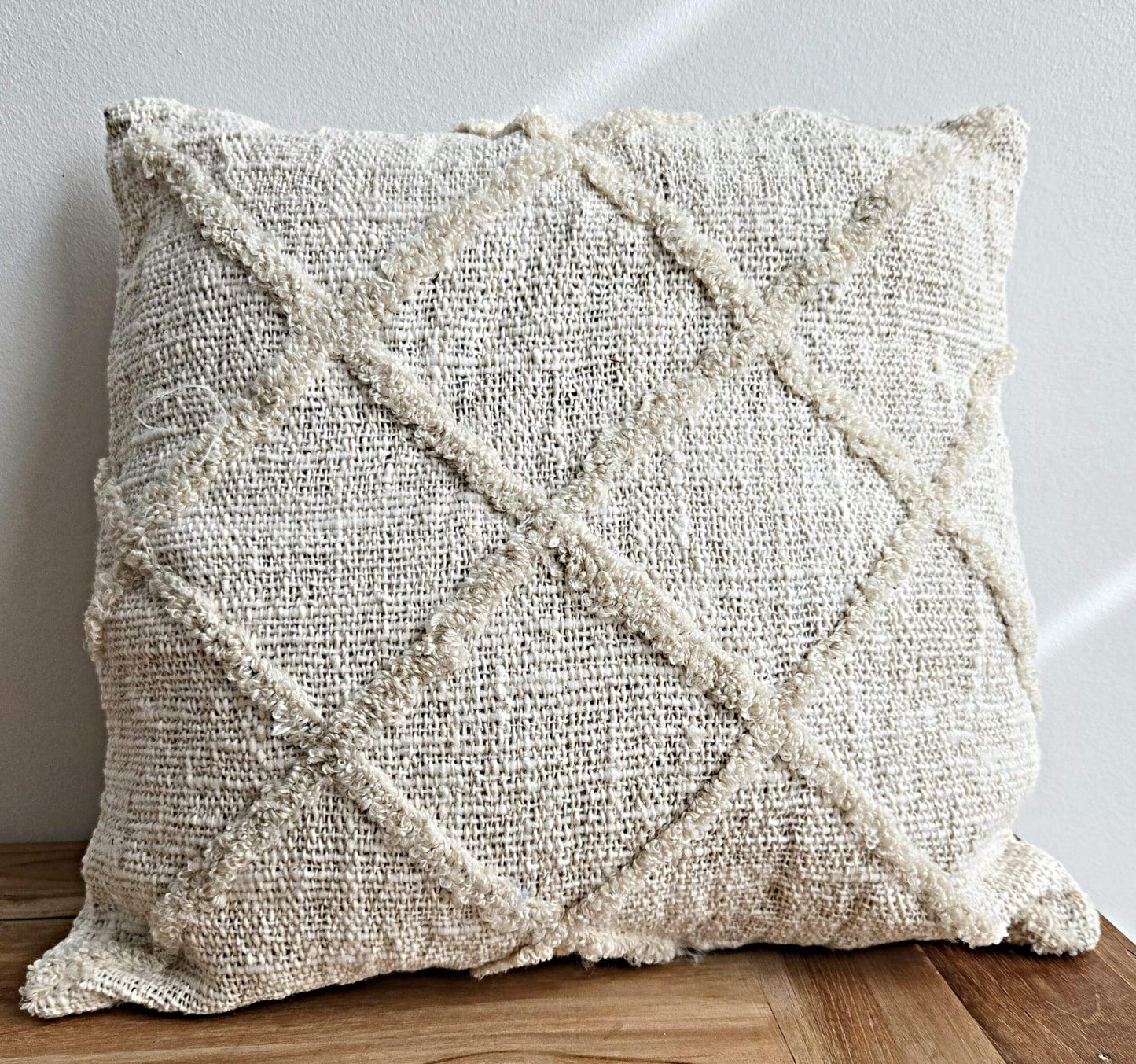 Coussin en tissu naturel avec motif géométrique texturé, idéal pour une décoration bohème chaleureuse.