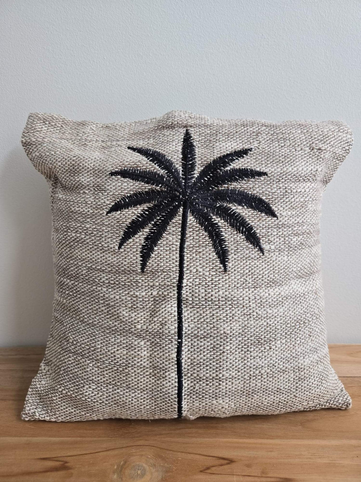 Coussin en tissu naturel avec palmier brodé, style bohème pour décoration intérieure.