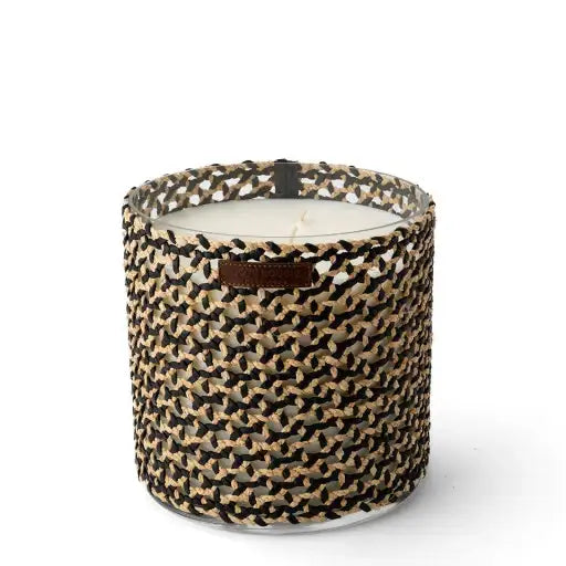Bougie parfumée dans un pot tressé noir et beige, style bohème artisanal.