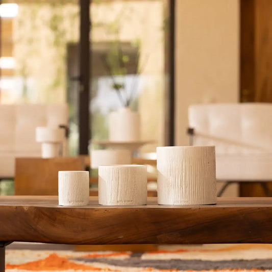 Trois pots en céramique texturée de tailles variées sur une table en bois, décoration intérieure naturelle.