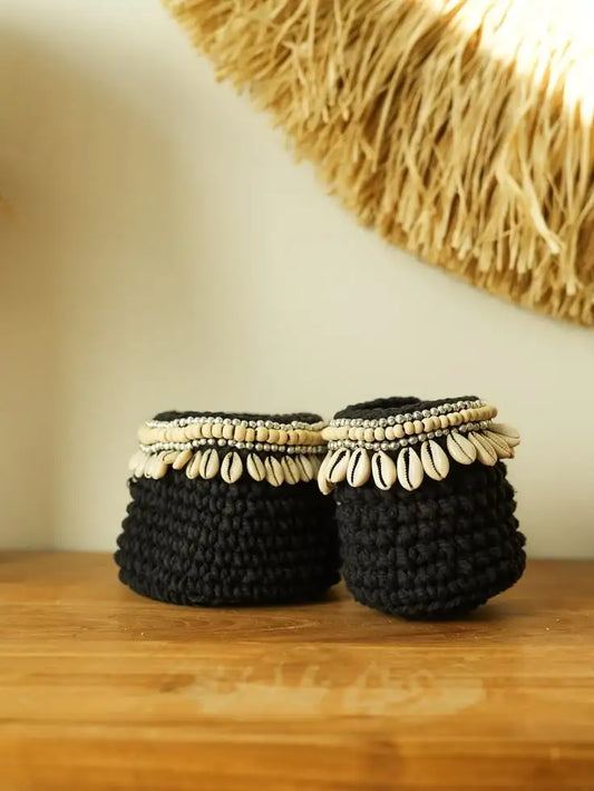 Paire de paniers tricotés noirs ornés de coquillages et perles, style bohème artisanal.